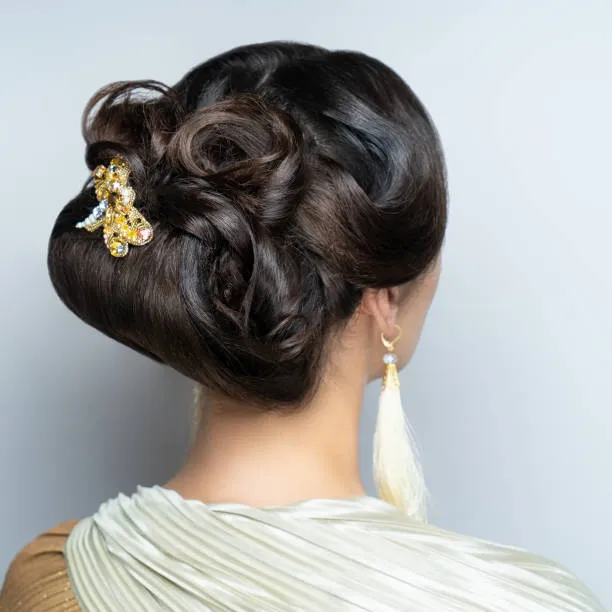 Back view of a bride with an infinity bun, twists arranged in graceful infinity symbol shape, architectural yet soft, clean studio background with soft lighting.
