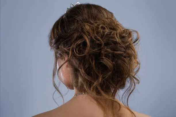 Side profile of a bride with naturally curly hair in a loose curly updo, voluminous and soft, warm skin tone, golden hour sunlight in a garden setting.