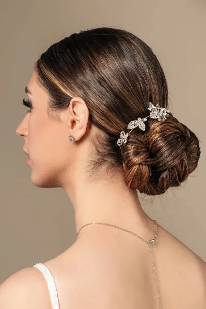Back view of a minimalist bride with a sleek low bun, clean lines, straight black hair, modern wedding dress, soft studio lighting with white architectural background.