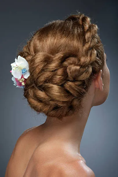  Back view of a bride with a twisted French chignon, sophisticated blend of French twist and traditional chignon, medium brown hair, elegant dressing room with window light.