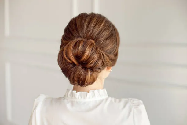 Side profile of a bride with a vintage bridal roll, smooth sides, softly rolled back, mid-century glamour, vintage lace dress and delicate veil, warm studio lighting.
