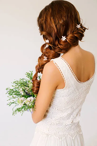 Back view of a bride with a sleek center-part bridal bun, minimalist style, perfectly smooth, modern satin gown, clean studio lighting with white background.