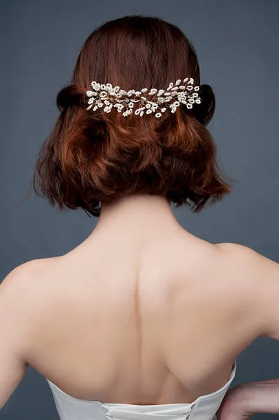 Portrait of a bride with classic bridal elegance, softly polished low chignon with face-framing curls, timeless sophistication, soft studio lighting with neutral elegant background.