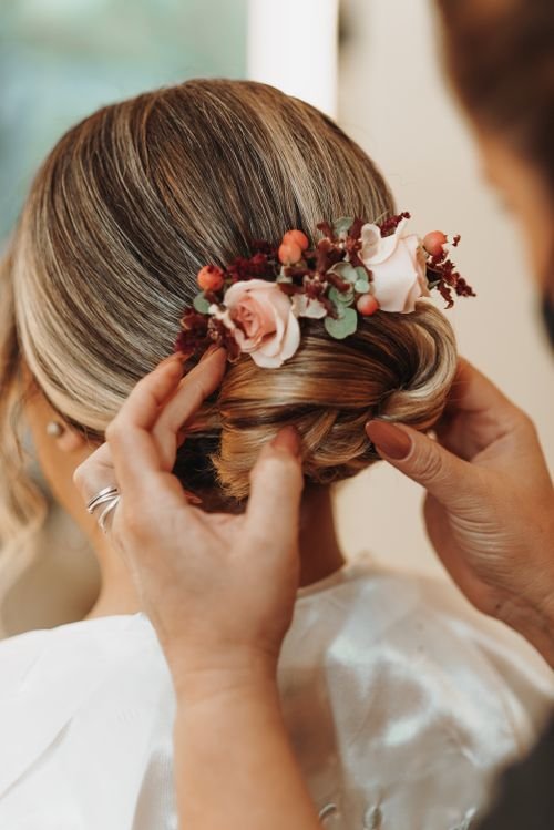 Free A close-up of a bride's elegant updo adorned with pink and red flowers, styled for a wedding. Stock Photo