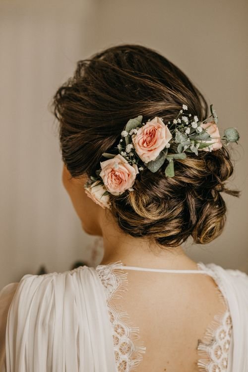Free Elegant bridal hairstyle showcasing an updo adorned with pink roses and greenery. Stock Photo