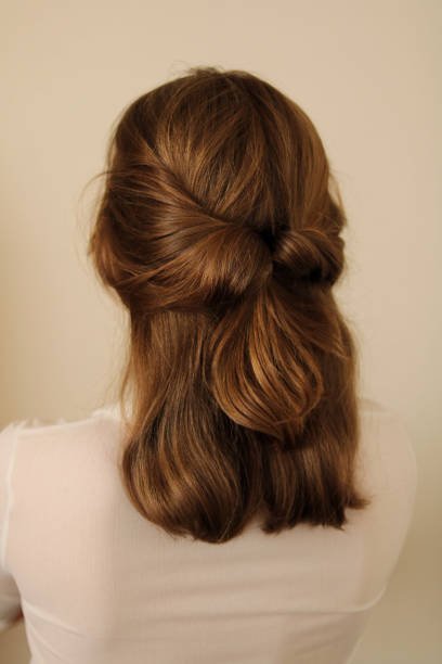 Young woman with healthy hair in a half-up hairstyle. Twisted half-up ponytail hairstyle. Casual hairstyle. White shirt. Back view of a hairstyle. No face. hairstyles woman stock pictures, royalty-free photos & images
